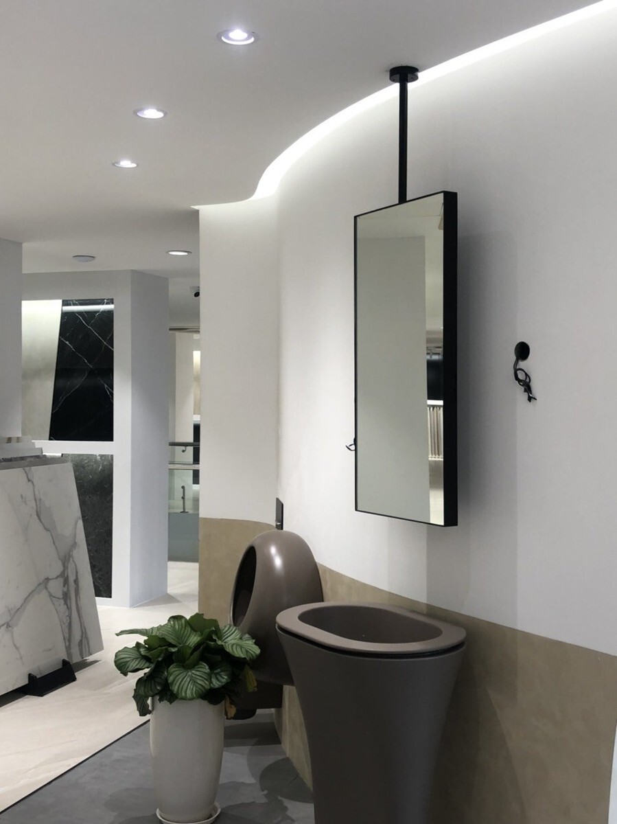 Gương chữ nhật treo bằng thanh phía trên chậu rửa màu tối, cạnh tường còn dây điện