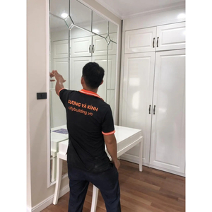 Người thợ thao tác bên mảng gương gần bàn và tủ. Hình tham khảo riêng của bài; quy cách và địa điểm không được xác nhận chỉ từ hình.