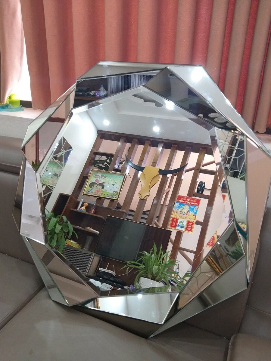 Gương tròn có khung ghép nhiều mặt phản chiếu dạng đa giác, đặt trên ghế sofa