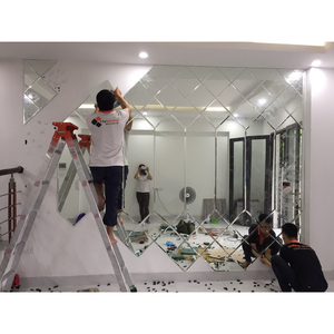 Người đứng trên thang thao tác ở phần trên của mảng gương ghép, với vật tư ở phía dưới.