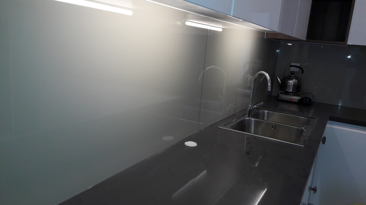 Mảng ốp xám được chiếu sáng dưới tủ bếp cạnh chậu rửa đôi