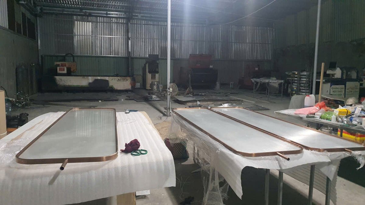 Nhiều tấm khung đặt trên bàn có lớp đệm trong khu vực gia công