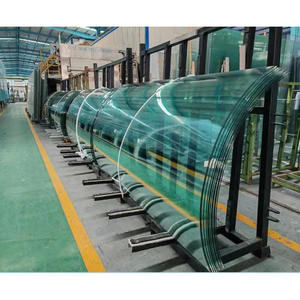 Các tấm kính cong xếp trên giá đỡ trong không gian sản xuất.