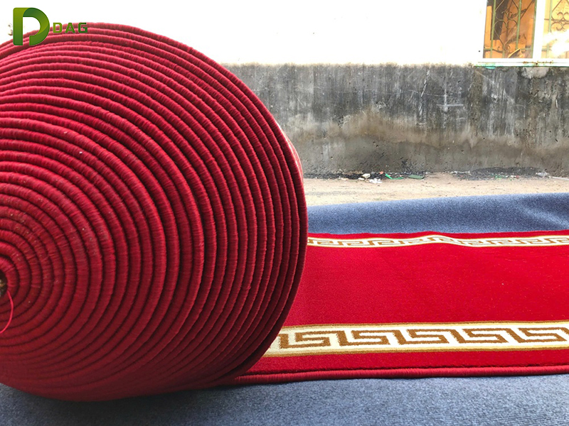 Kỹ thuật viên thi công lăn keo acrylic polyme và căng nén màng thảm cuộn trải sàn Hà Nội bằng Power Stretcher.