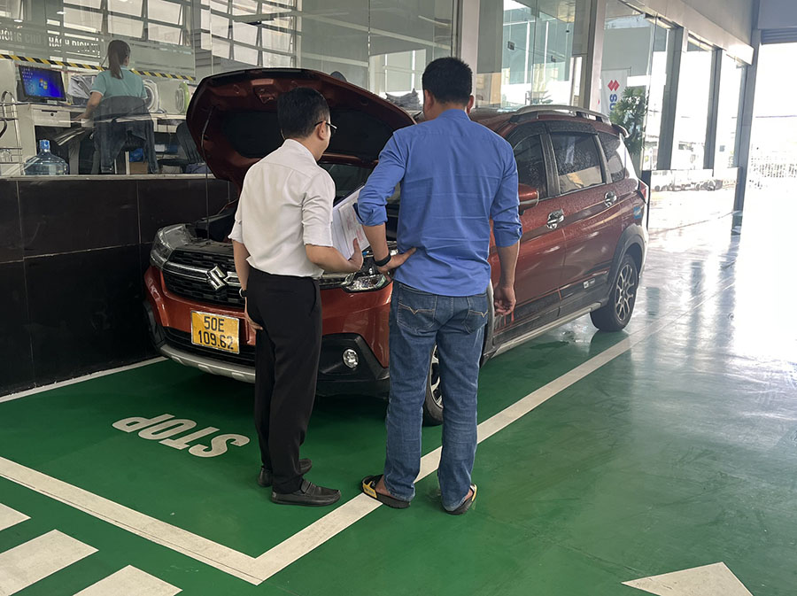 Cố Vấn Dịch Vụ đang tư vấn bảo dưỡng thay nhớt cho xe Suzuki XL7 Hybrid Tại Showroom Suzuki Việt Long