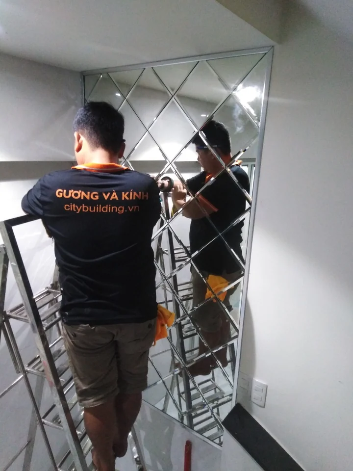 Nhân viên Citybuilding đứng trên thang thao tác với gương ghép hình thoi.